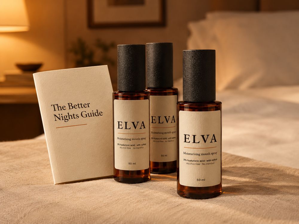 Three bottles of ELVA and The Better Nights Guide on a bed in warm lamplight